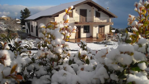 A two-story house with a balcony, surrounded by snow-covered plants. - Aurora dell'Etna (Zafferana Etnea)