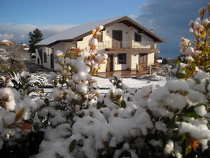 A two-story house with a balcony, surrounded by snow-covered plants. - Aurora dell'Etna (Zafferana Etnea)