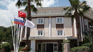 The exterior of the Rivero Hotel with a symmetrical facade, columns, and a statue of a lion.