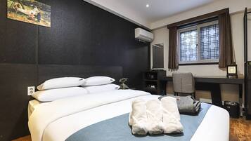 A hotel room with a bed, a desk, a chair, and a window with a view.