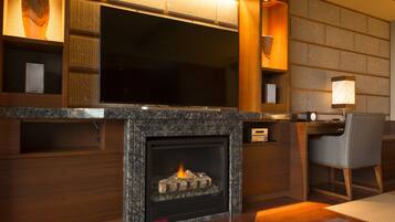 A modern living room with a fireplace, wooden shelving, a flat-screen TV, and a comfortable seating area.