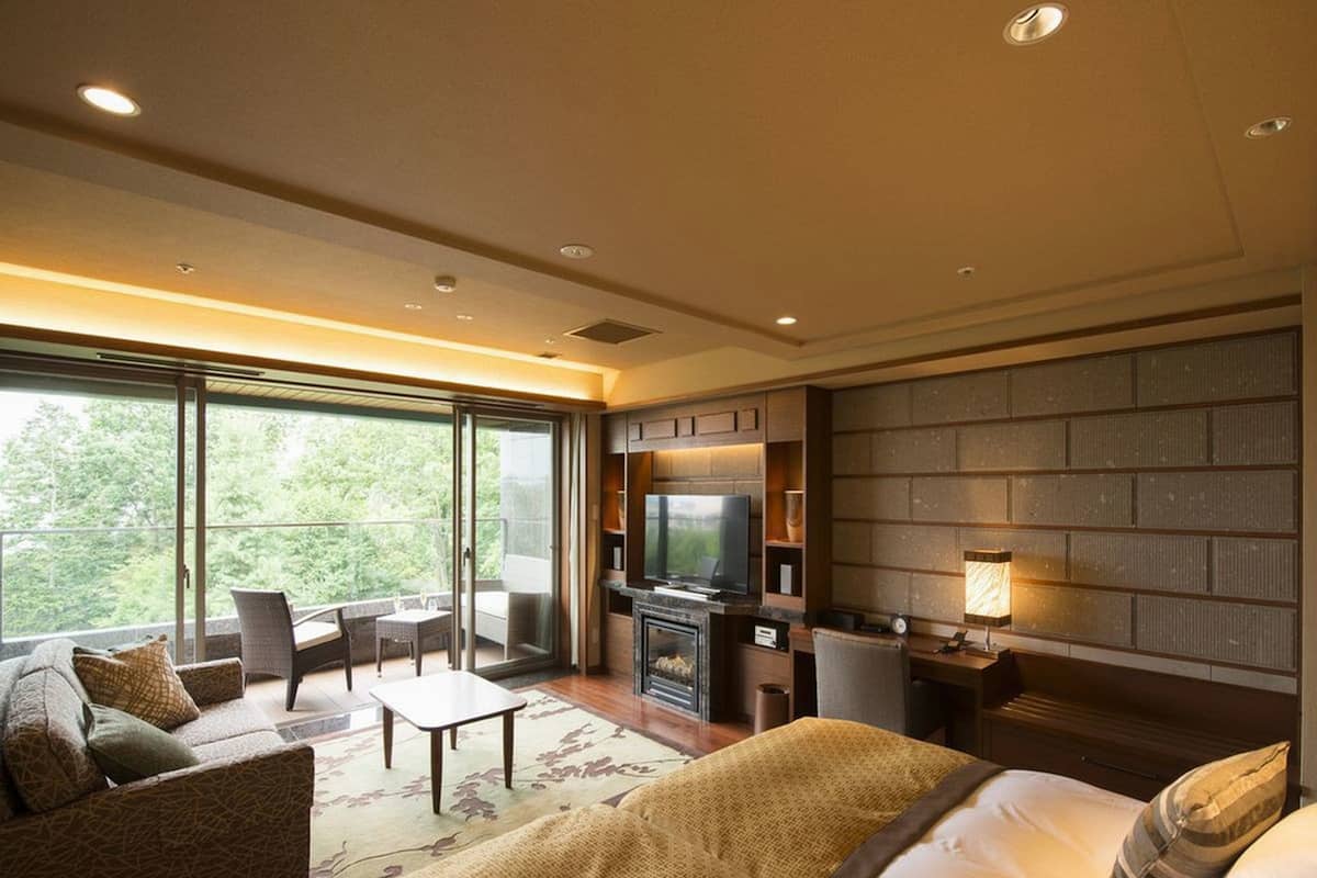 Ein modernes Hotelzimmer mit einem großen Bett, einer Couch, einem Esstisch und einem Fernseher.