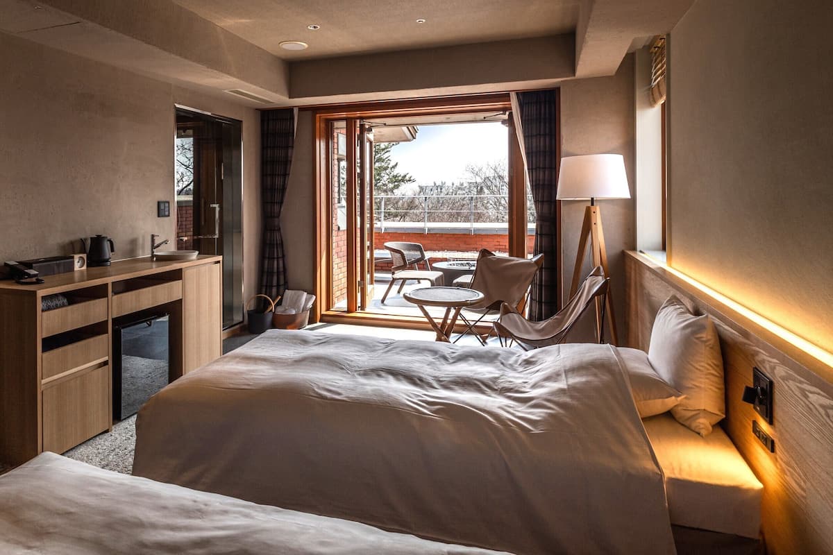 Ein Hotelzimmer mit einem großen Bett, einem Schreibtisch mit Wasserkocher, einem Stuhl und Blick ins Freie.