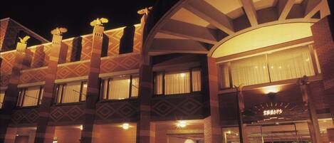 Un hotel con un diseño arquitectónico distintivo, que presenta una fachada curva y varios balcones con detalles decorativos.