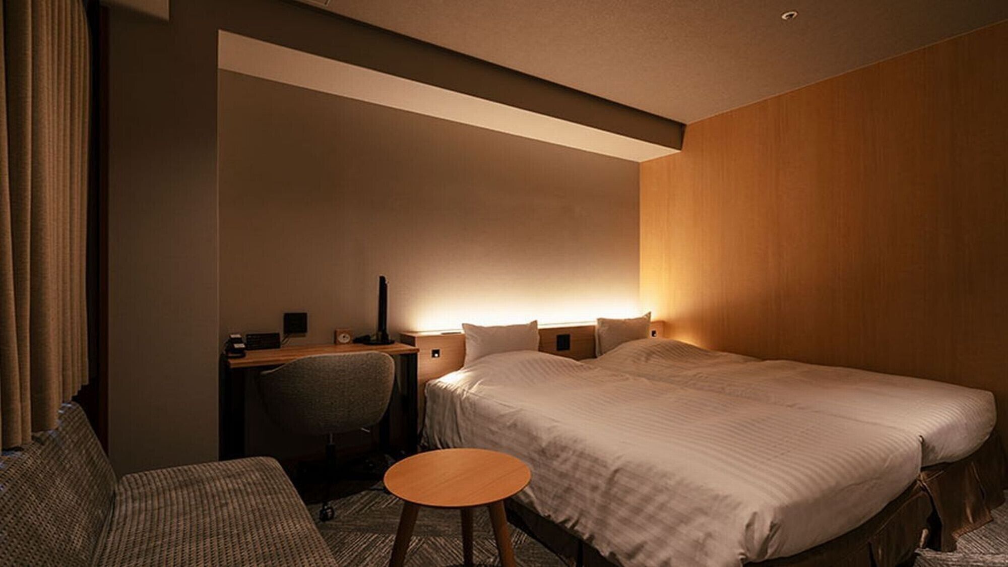 A hotel room with a bed, desk, chair, and a small round table.