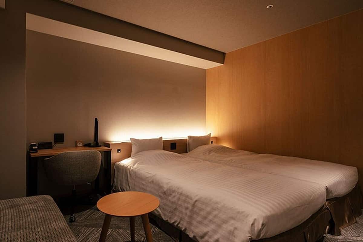 Ein Hotelzimmer mit Bett, Schreibtisch, Stuhl und einem kleinen runden Tisch.