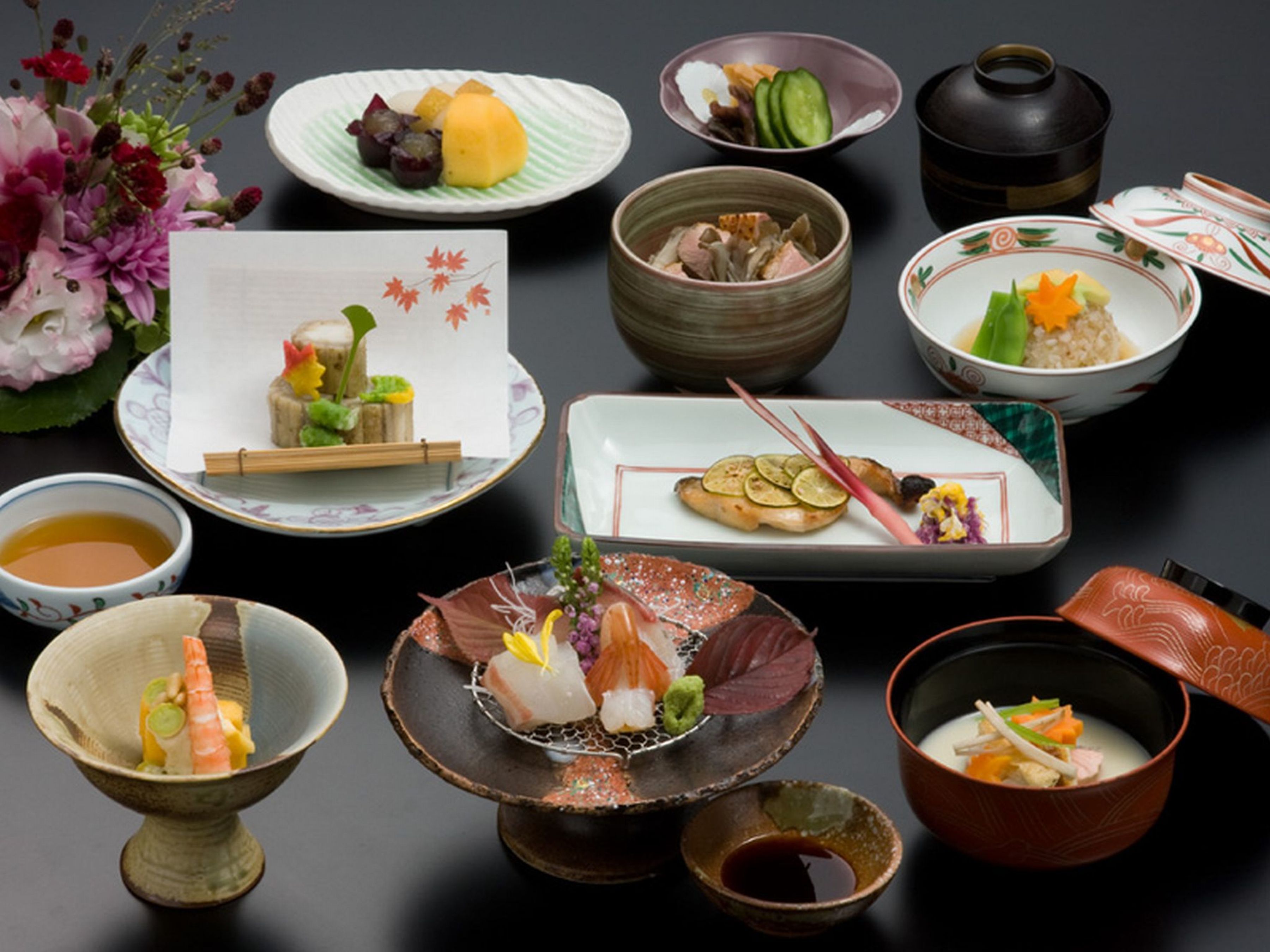 Une variété de plats et d’ustensiles de cuisine traditionnels japonais sont disposés sur une table.
