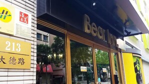 Exterior del Bear Inn con un amplio acceso de vidrio, un cartel que indica la habitación número 213 y una señal de calle visible.