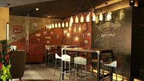 Zona de bar con taburetes, mostrador y lámparas colgantes.