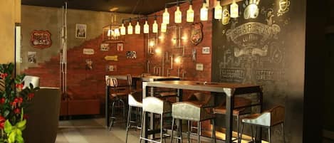 A bar area with stools, a bar counter, and hanging light fixtures.