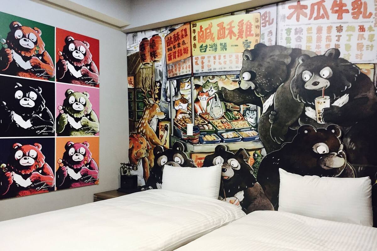 Une chambre avec un lit, un mur orné de plusieurs affiches sur le thème des ours, et une grande fresque murale représentant un ours.