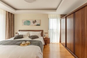 Une chambre à coucher avec un grand lit, une table de chevet, une armoire en bois et un tableau accroché au mur.