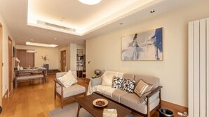 A modern living room with a sofa, armchairs, a coffee table, and a painting on the wall. - Green Court Place Jinqiao Middle Ring Shanghai (Shanghai)