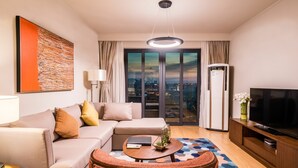 A modern hotel room with a sofa, a coffee table, a TV, and a city view through the windows. - Green Court Place Jinqiao Middle Ring Shanghai (Shanghai)