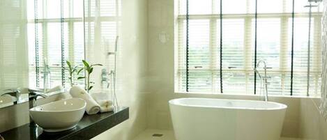 Une salle de bain moderne avec une baignoire sur pieds, un grand miroir et une fenêtre avec des stores.