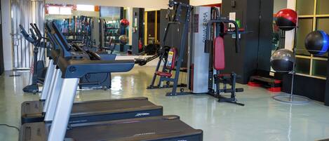 A gym with treadmills, weight machines, and exercise balls.
