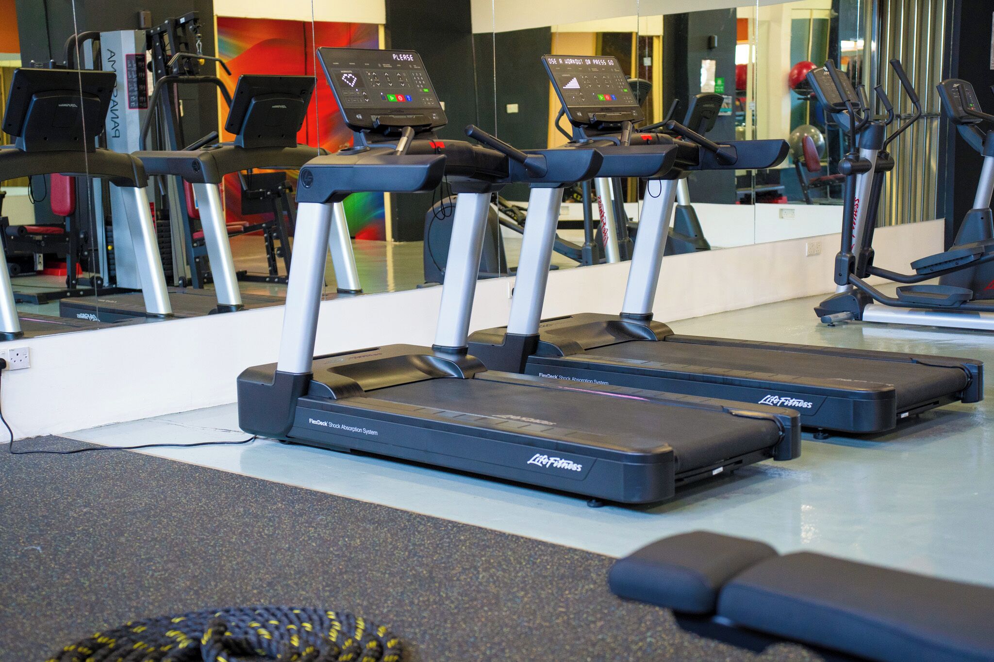 A gym with multiple treadmills, a mirrored wall, and exercise equipment.