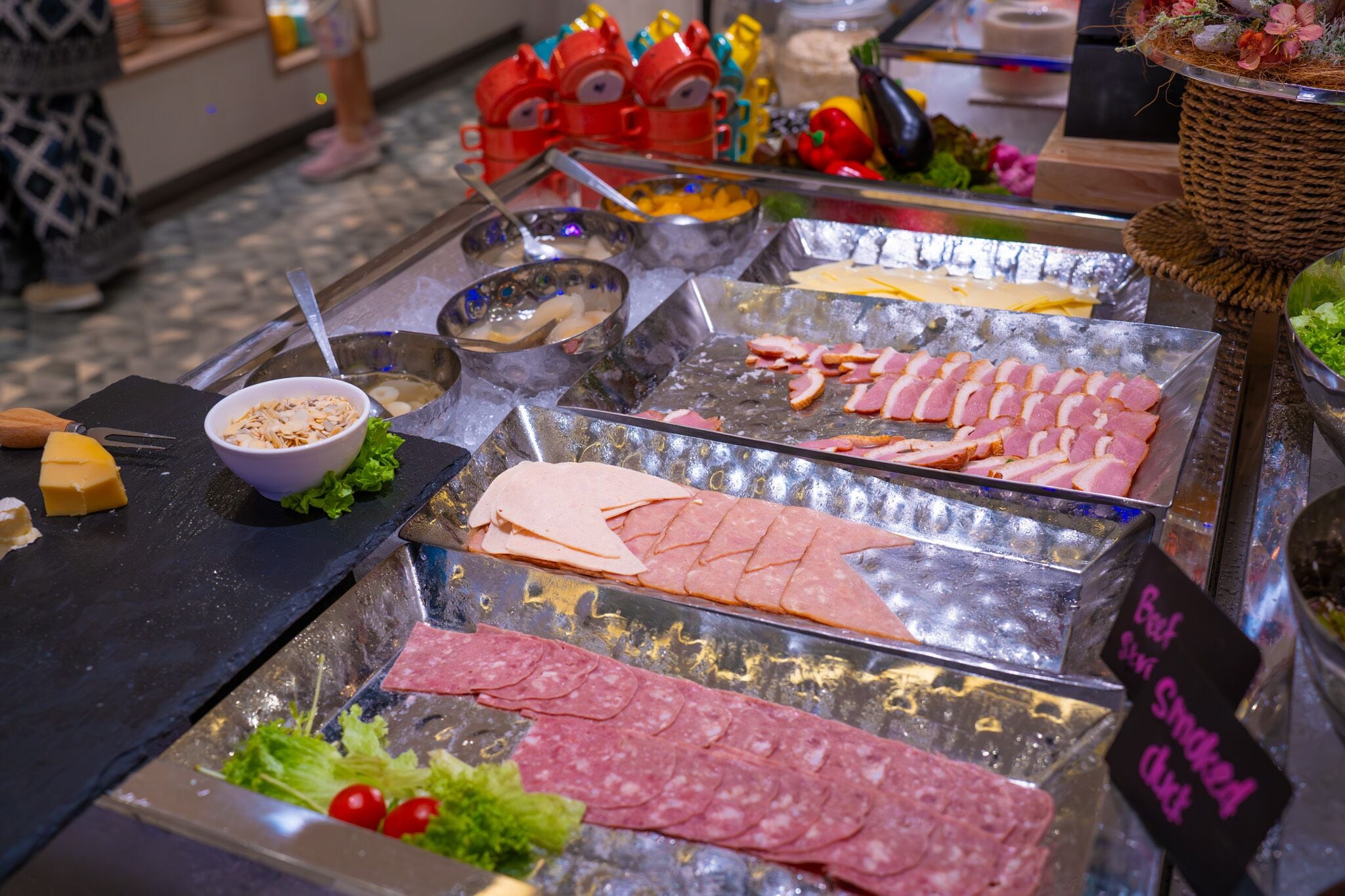 A deli counter with various meats and cheeses displayed on trays.