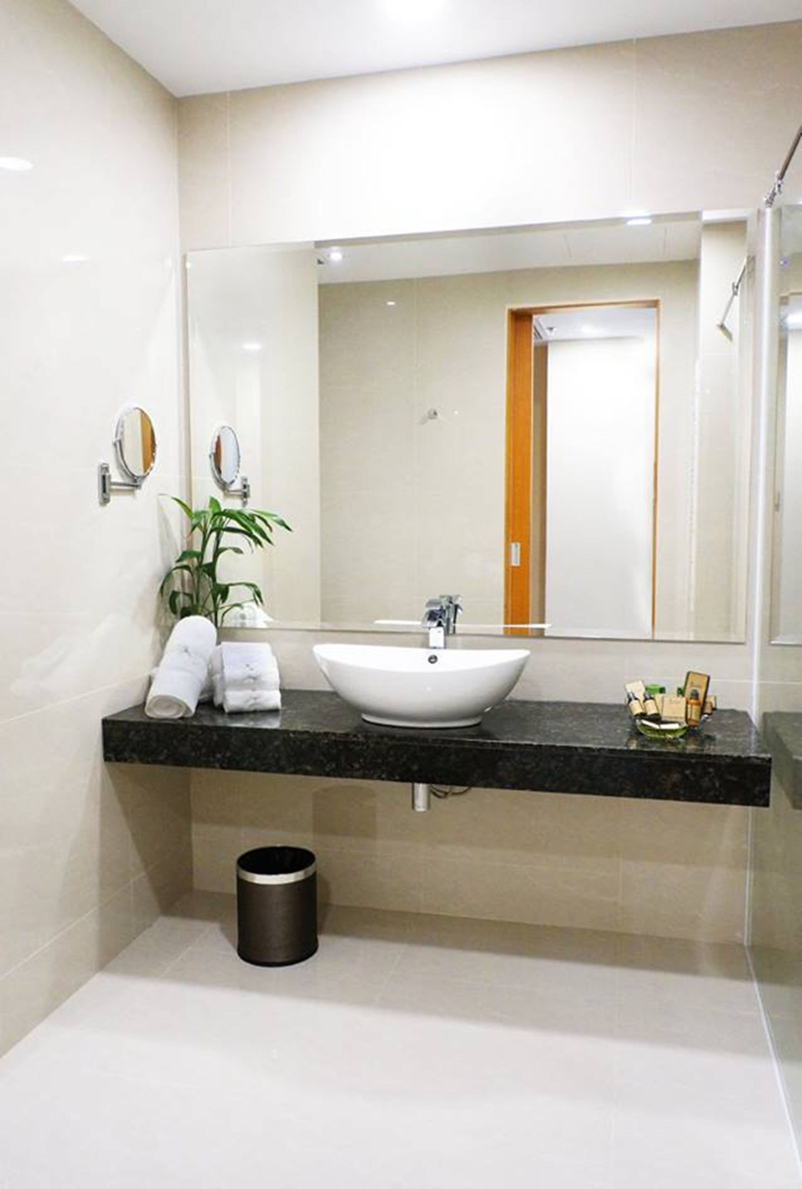 A modern bathroom with a white sink, black countertop, and a mirror above it.