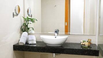 A modern bathroom with a white sink, black countertop, and a mirror above it.