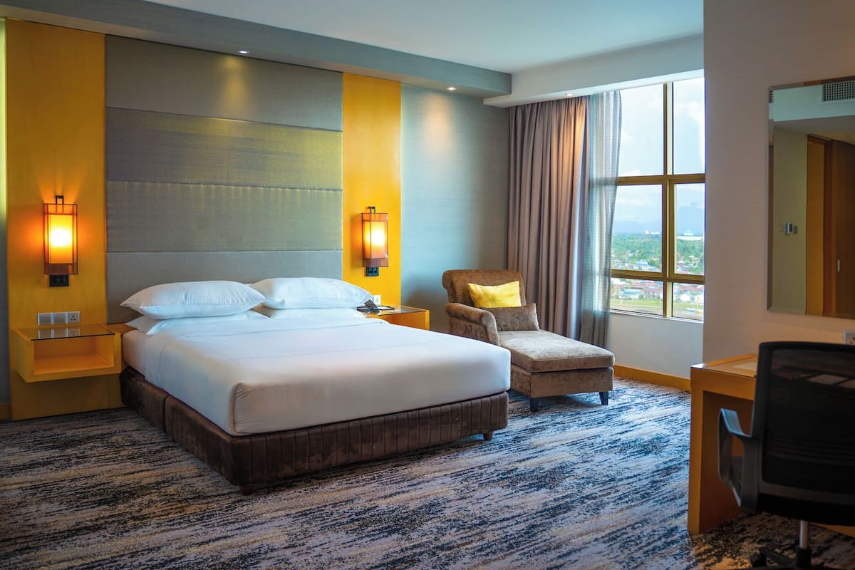 A hotel room with a large bed, two bedside lamps, a chair, a desk, and a large window with a view.