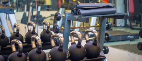 Uma academia com halteres, um banco e equipamentos de exercícios.