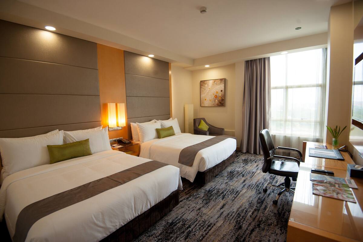A hotel room with two beds, a desk, and a chair.