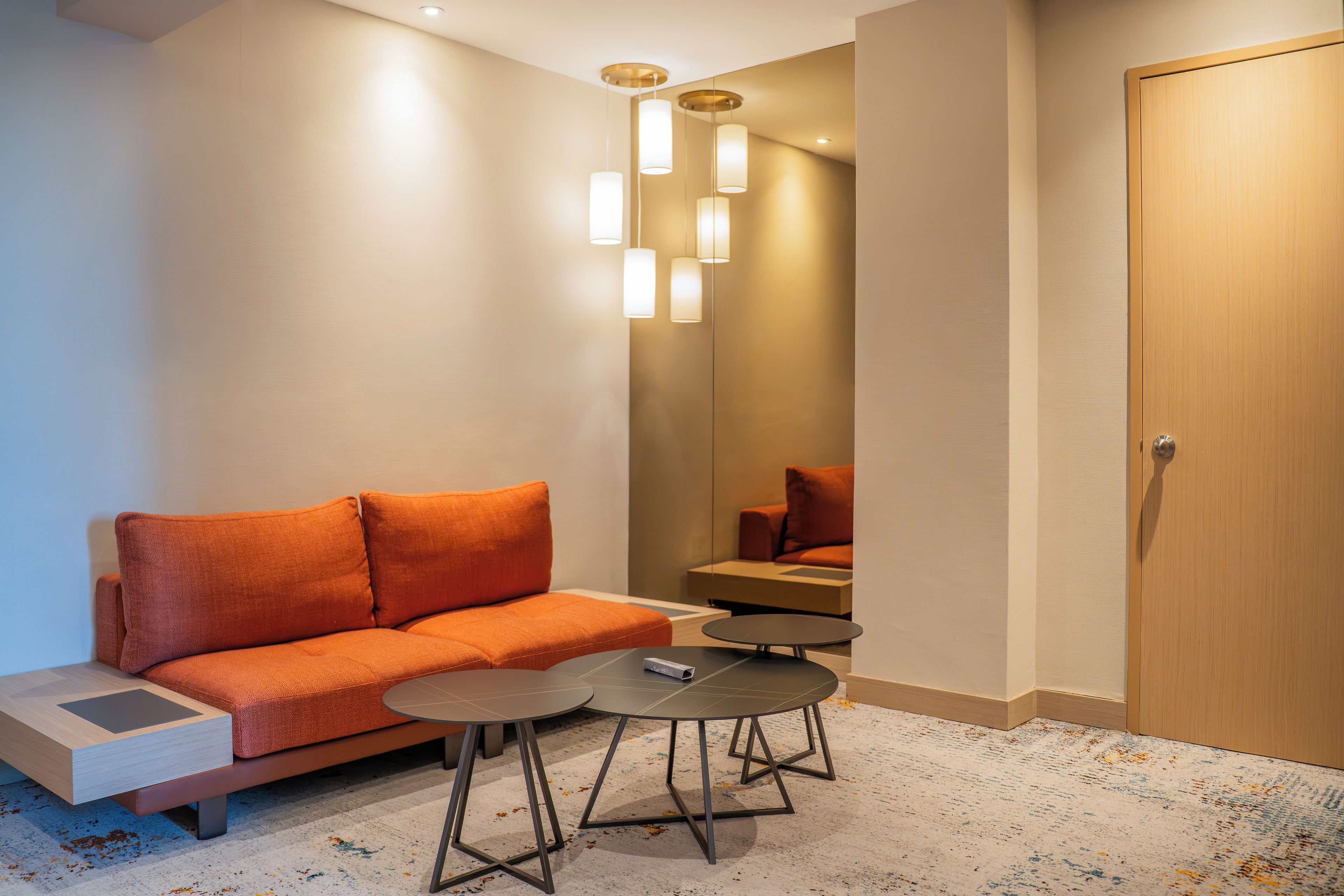Una habitación de hotel moderna con un sofá, una mesita redonda y una puerta.