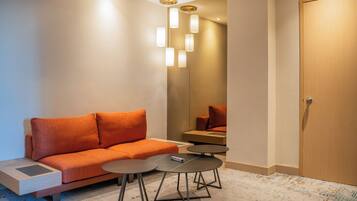 Una habitación de hotel moderna con un sofá, una mesita redonda y una puerta.