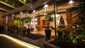 Eine moderne Hotelhalle mit großzügigem Design, üppigen Topfpflanzen und einer zentralen Sitzecke.