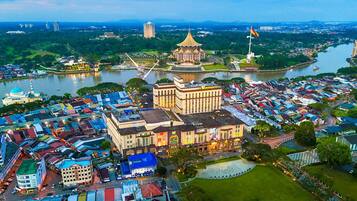 A waterfront hotel with a prominent tower, a large open plaza, and a river in the background.