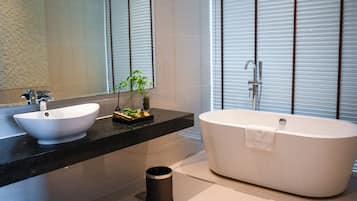 A modern bathroom with a large white bathtub, a white sink, and a black countertop.