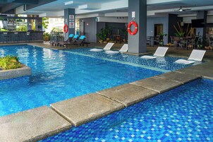 Una piscina con sillas de descanso, un bar y plantas en macetas.