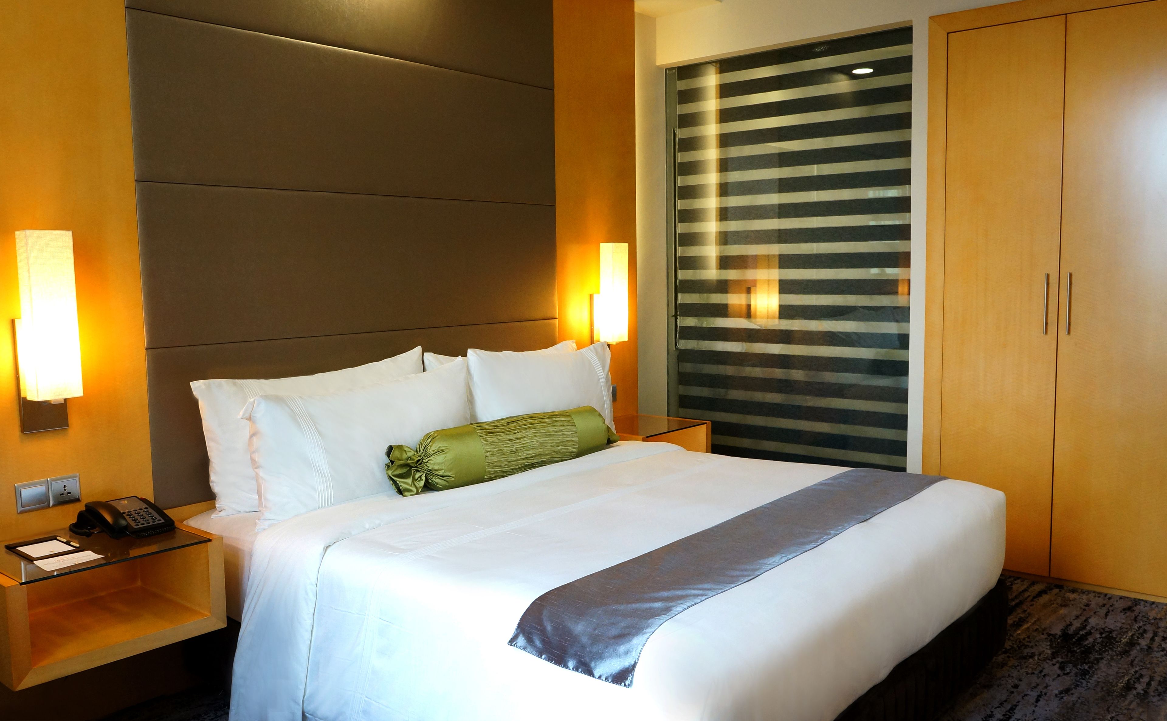 A hotel room with a large bed, two bedside tables, a telephone, and a nightstand.