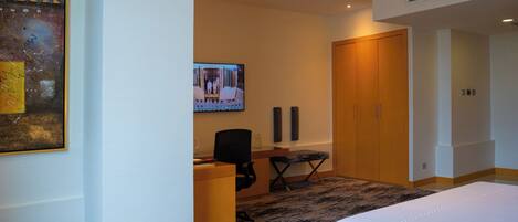 A hotel room with a bed, a desk, a chair, a television, and a wardrobe.