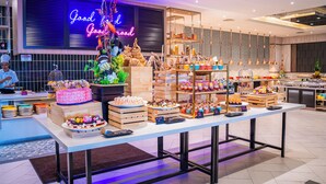 Eine Bäckertheke mit verschiedenen Backwaren und einem Neon-Schild mit der Aufschrift 'Good Food Good Mood'.