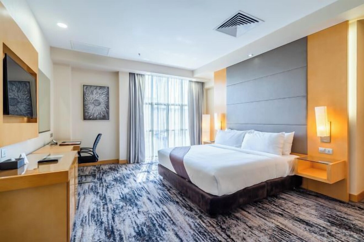 Una habitación de hotel moderna con una cama grande, un escritorio y una silla.