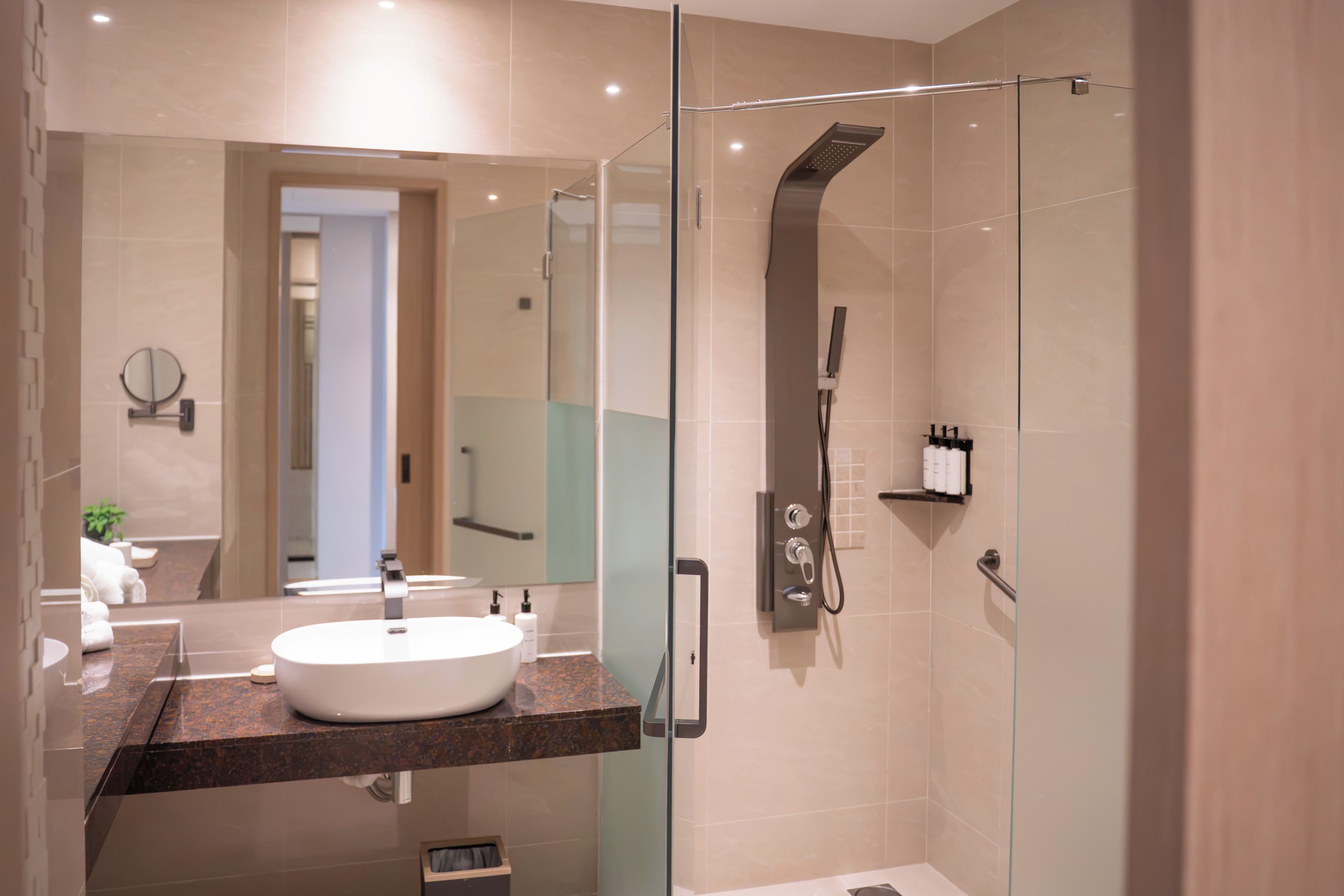A modern bathroom with a glass-enclosed shower, a white sink, and a mirror.