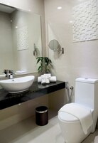 Um banheiro moderno com uma pia grande e branca, vaso sanitário e espelho.