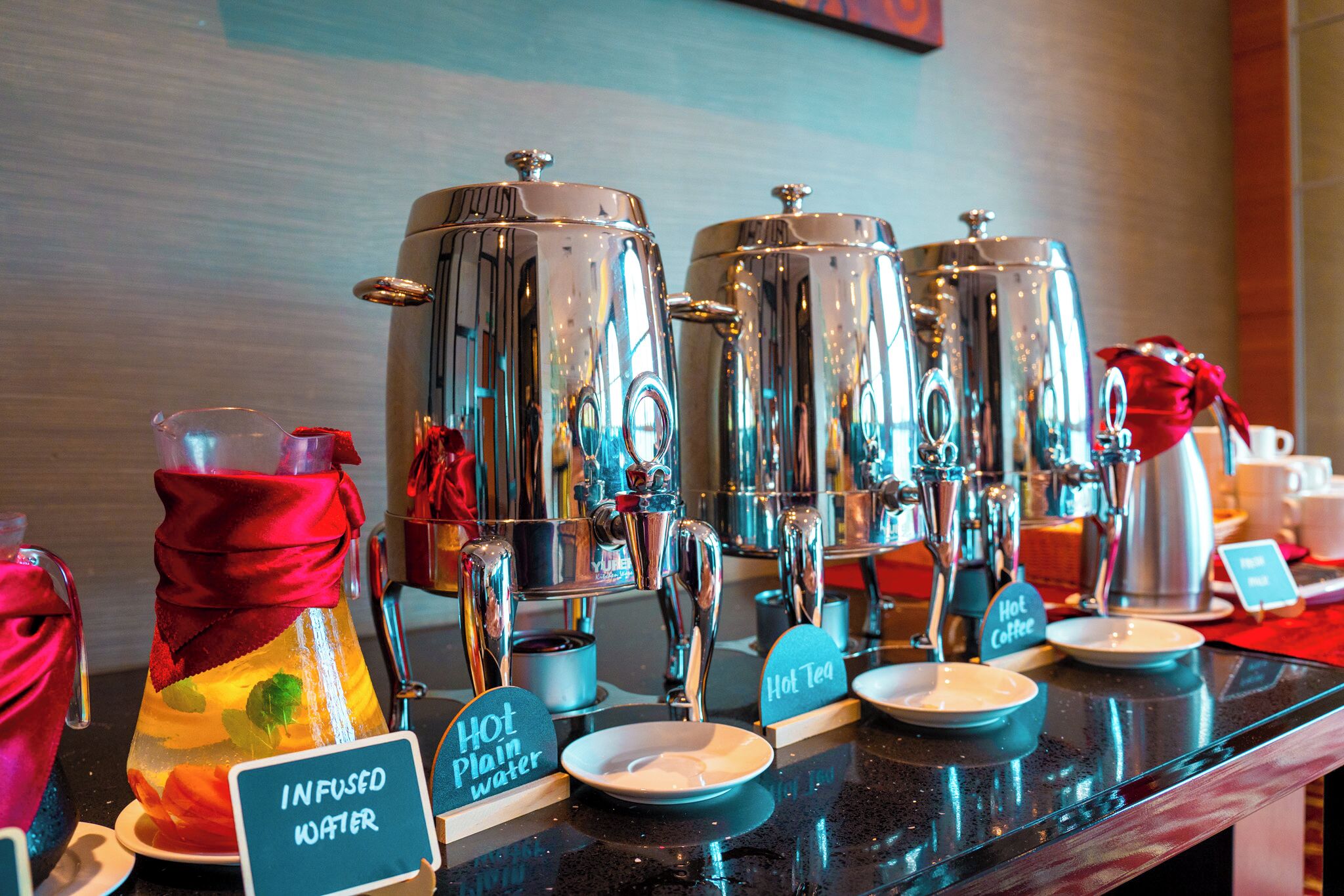 Ein Kaffee-Bereich mit mehreren Kaffee-Automaten, Schildern für heiße Tee- und Kaffeeauswahl sowie einem Schild für Infused Water.