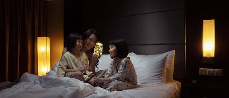 A hotel room with a bed, a nightstand, and a wall-mounted lamp.