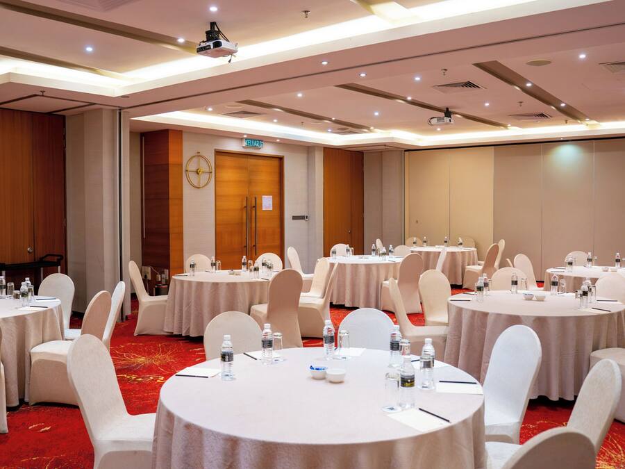 A conference room with multiple round tables, white chairs, and water bottles.