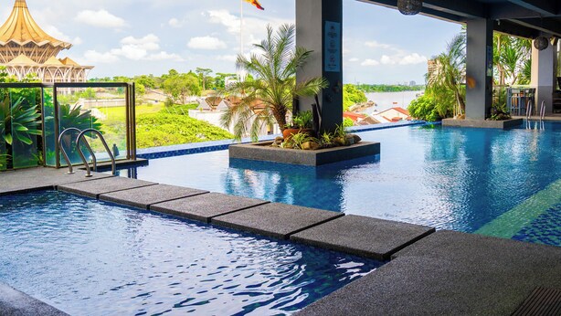 Ein Swimmingpool mit klarem, blauem Wasser, eine Flagge und der Blick auf ein traditionelles Gebäude.
