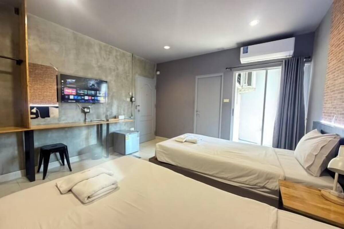 Ein modernes Hotelzimmer mit Bett, Schreibtisch, Fernseher und Fenster.