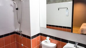 Een badkamer met douche, toilet, wastafel en spiegel.