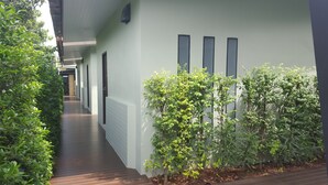 Un pasillo con suelo de madera, paredes blancas y plantas verdes.