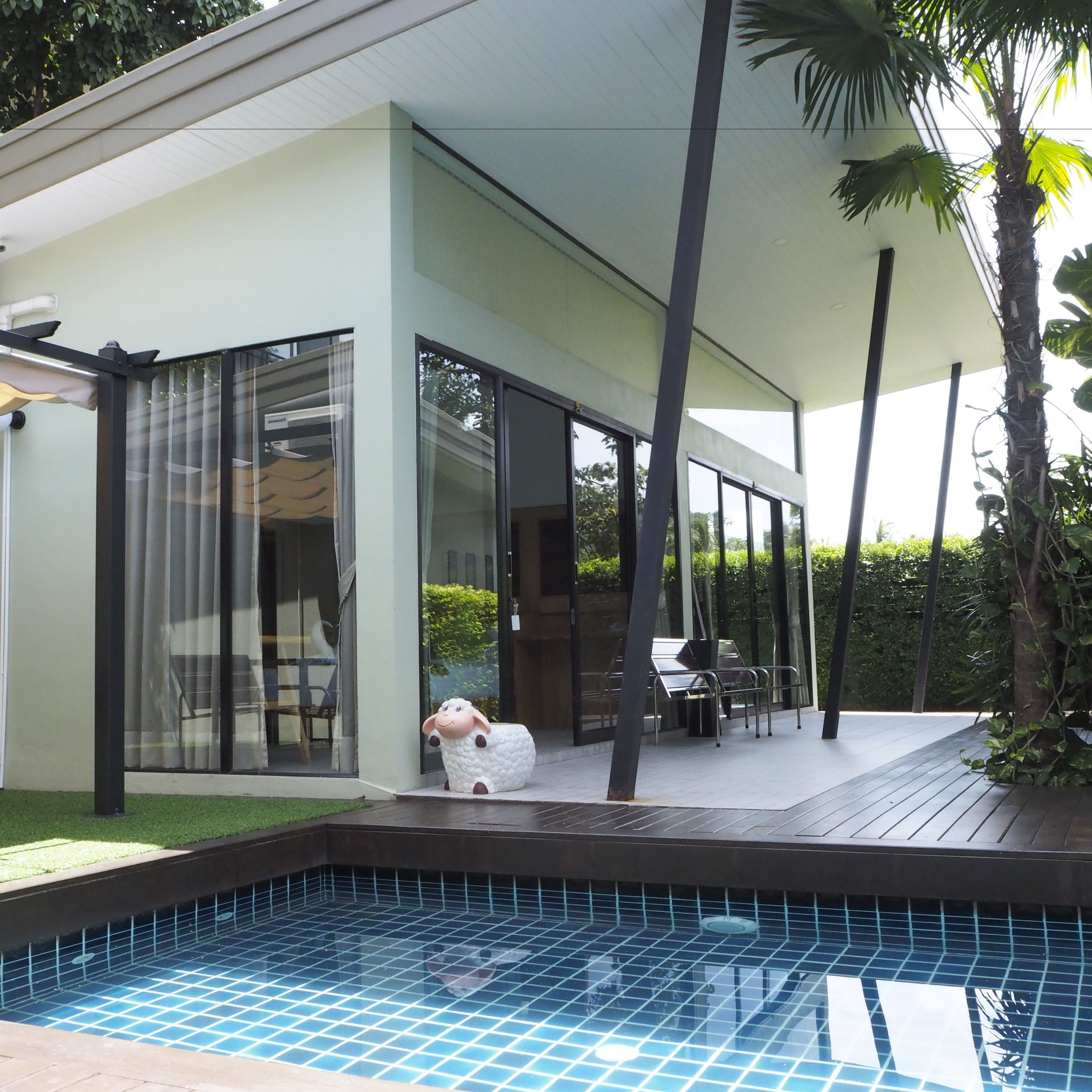 A modern house with a swimming pool, large glass doors, and a patio area.