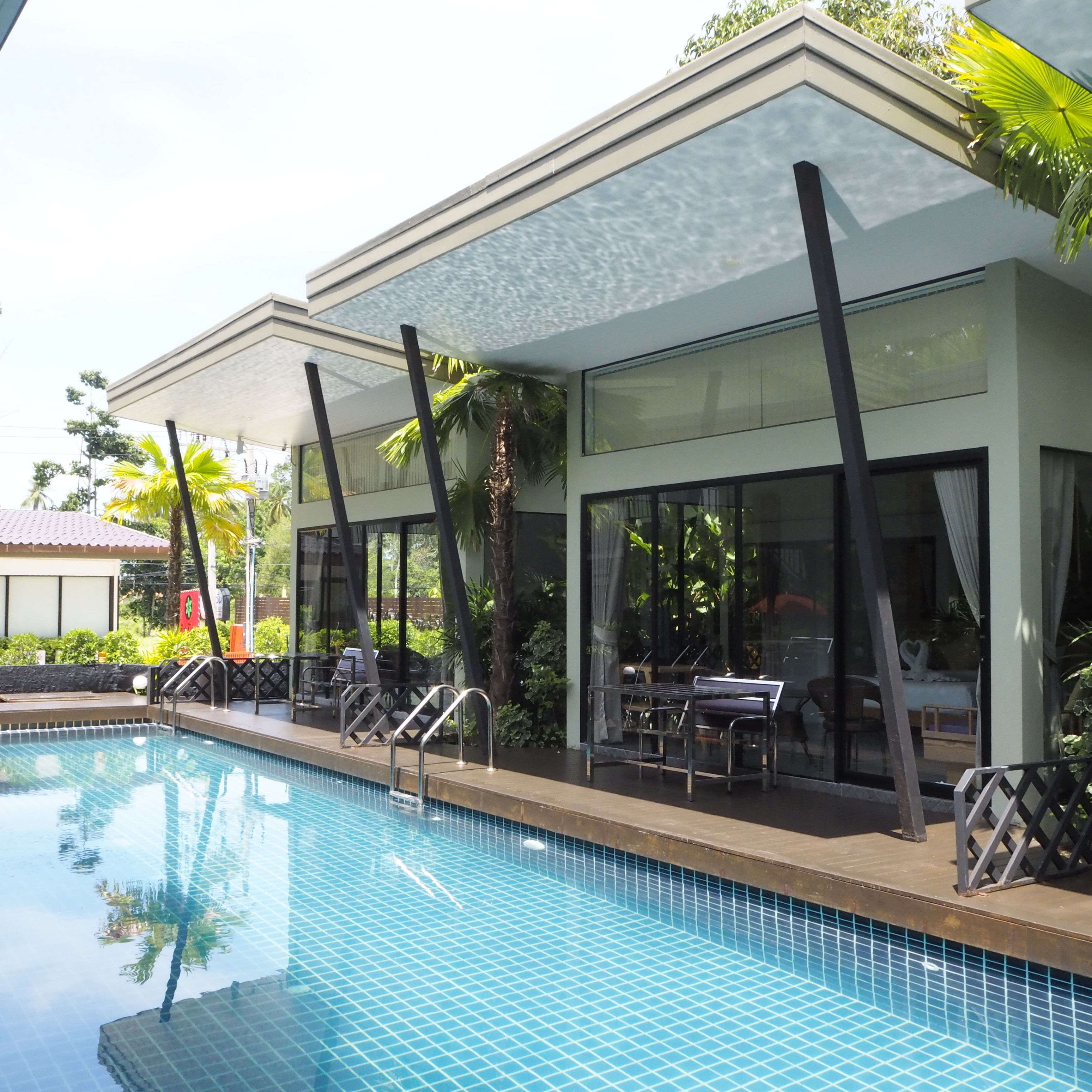 Un hotel moderno con piscina, zona de estar al aire libre y amplias ventanas.