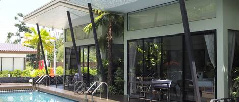 Un hotel moderno con piscina, zona de estar al aire libre y amplias ventanas.