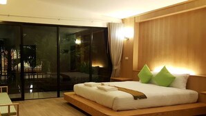 Un dormitorio moderno con una cama grande, cabecera de madera y puerta de cristal corredera que da a un balcón.